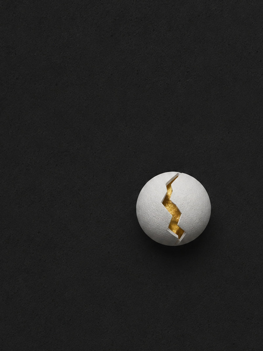 A minimalist poster featuring a cracked gold ball on a dark background.