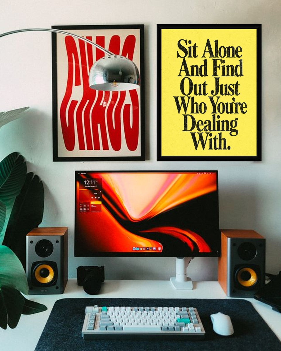 The 'Sit Alone And Find Out' poster displayed on a stylish office wall, showcasing its vibrant design.
